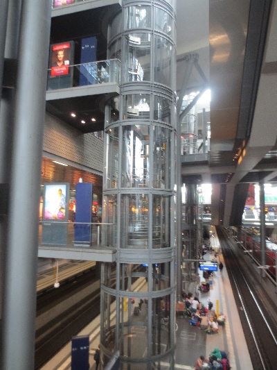 [Berlin]Access to by platforms is by escalators from the mezzanine concourse augmented by these glass lifts providing direct interchange between the two rail levels without needing to use the concourse and access from all floors for the mobility impaired.  Photo by Ian Brown for Railfuture.