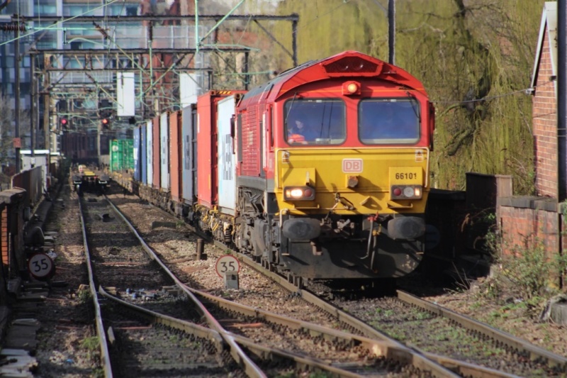 A Trafford Park to Southampton Western Docks freight train approaches Platform 13 at Manchester Piccadilly. To the left is the rear of a train to Trafford Park from London Gateway.